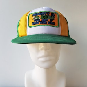 May include: A white ceramic mug with a black handle and the text "But First, Coffee" in a bold, black font. The mug is set against a blurred background, suggesting a cozy setting. The mug appears to be approximately 4 inches tall.