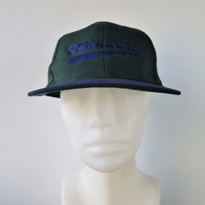 May include: A dark green baseball cap with a navy blue brim and the word "Compulware" embroidered in blue script. The cap is displayed on a white mannequin head.