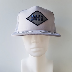 May include: A grey and black mesh trucker hat with a diamond-shaped patch that says "MH TRANSPORT LTD".