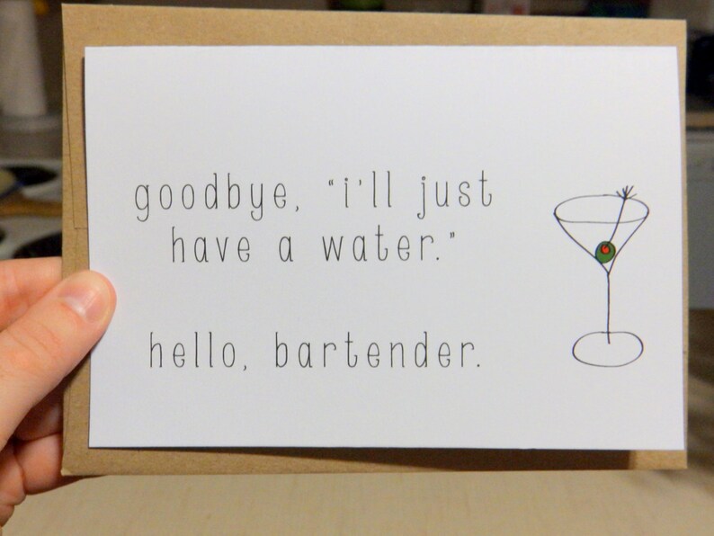 May include: A white greeting card with the text "goodbye, 'I'll just have a water.' hello, bartender." A simple drawing of a martini glass with an olive is on the right side. The card is held by a hand.