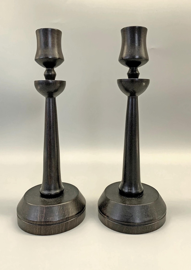 Pode incluir: Um par de casti&ccedil;ais de madeira castanho escuro com um design simples e elegante. Cada casti&ccedil;al tem uma base larga, um caule alto e fino e uma parte superior em forma de ta&ccedil;a.