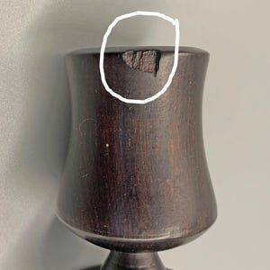 Pode incluir: Um c&aacute;lice de madeira castanho escuro com um pequeno lascado na borda.