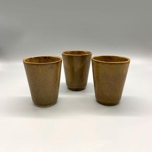 May include: Three brown ceramic cups with a textured surface.