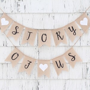 May include: A burlap banner with the words "STORY OF US" in black lettering. The banner is strung with twine and has white felt hearts between each letter.