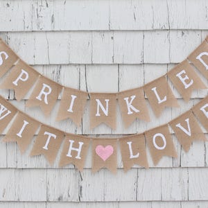 May include: A burlap banner with pink hearts and the text "SPRINKLED WITH LOVE" in white letters.