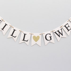 May include: White banner with black letters spelling "WILL" and "GWEN" with a gold glitter heart in between.