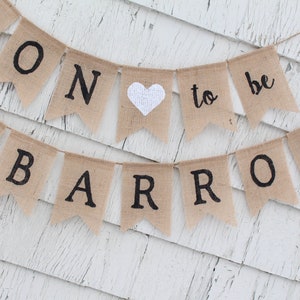 May include: A burlap banner with the text "Soon to be Barron" in black lettering. The banner has two white hearts and is strung with twine.