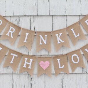 May include: A burlap banner with the text "SPRINKLED WITH LOVE" in white letters. The banner has a pink heart in the middle of the text.