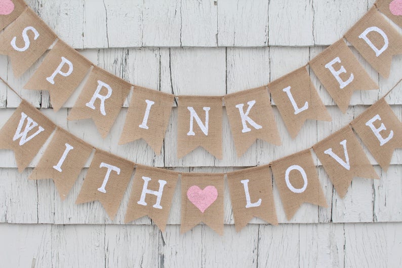 May include: A burlap banner with the text "SPRINKLED WITH LOVE" in white letters. The banner has a pink heart in the middle of the text.