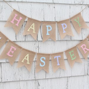 May include: A burlap banner with the words "Happy Easter" in pastel colors. The banner is decorated with white bunny silhouettes.