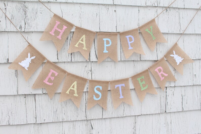 May include: A burlap banner with the words "Happy Easter" in pastel colors. The banner is decorated with white bunny silhouettes.