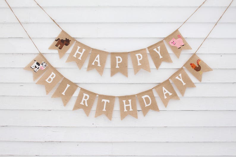 May include: A burlap banner with the words "Happy Birthday" in white letters. The banner is decorated with farm animal illustrations, including a cow, pig, horse, and rooster.