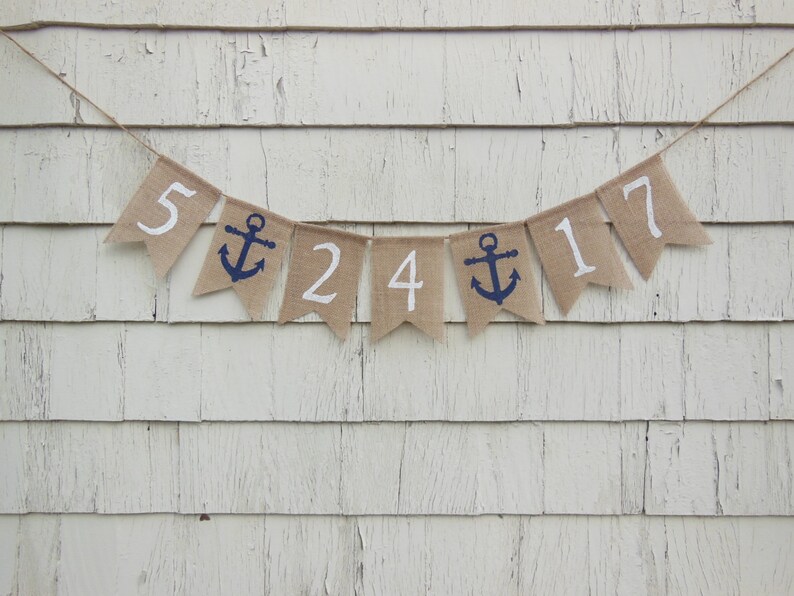 May include: A burlap banner with white numbers and a blue anchor, spelling out "5 24 17".