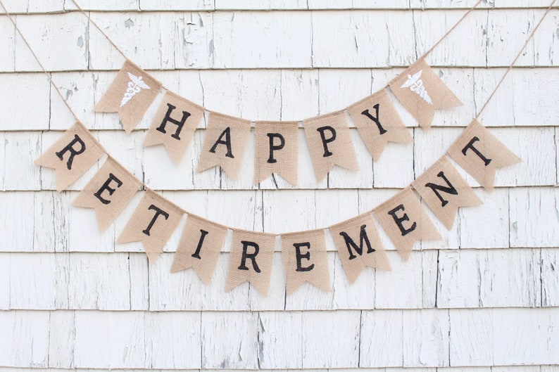 May include: A burlap banner with the words "Happy Retirement" in black lettering. The banner is decorated with two small white medical caduceus symbols.