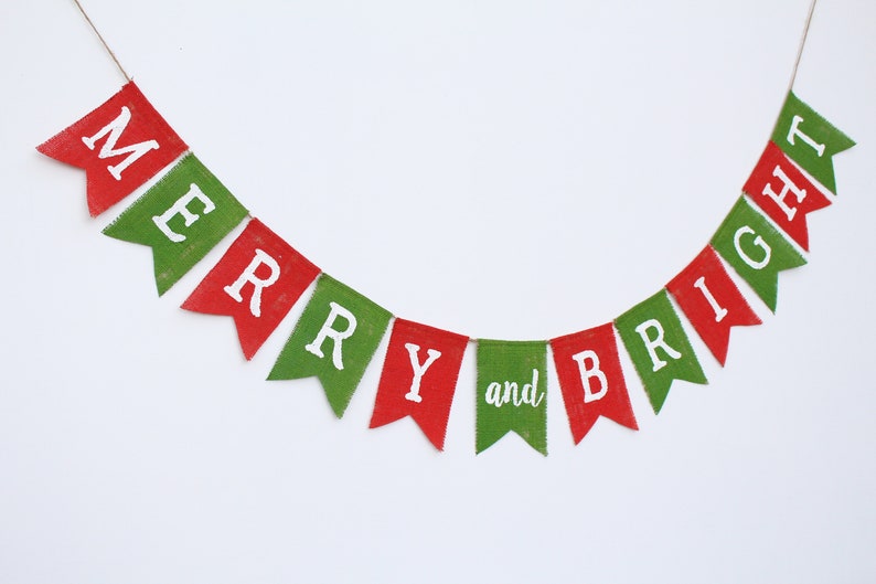 May include: A festive banner with red and green pennants spelling "MERRY and BRIGHT" in white letters. The banner is strung on a thin twine, perfect for holiday decorations. The pennants have a textured, burlap-like appearance.