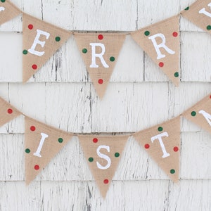 May include: A festive burlap banner spelling "MERRY CHRISTMAS" in white capital letters. Each triangular flag is adorned with red and green dots. The banner is set against a white, weathered wooden backdrop.