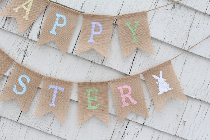 May include: A burlap banner with the words "Happy Easter" in pastel colors. The banner also features a white silhouette of a bunny rabbit.