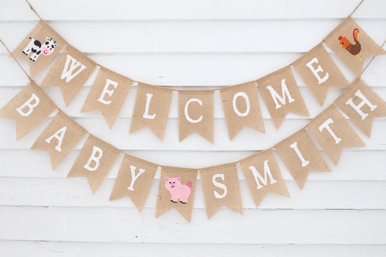 Pode incluir: Uma faixa de serapilheira com as palavras "WELCOME BABY SMITH" em letras brancas. A faixa &eacute; decorada com uma vaca, um porco e um galo. Perfeita para um ch&aacute; de beb&eacute; ou para decorar o quarto do beb&eacute;.