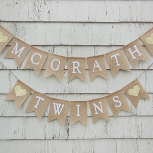 May include: A burlap banner with the text "McGrath Twins" in white letters. The banner is decorated with small yellow hearts.