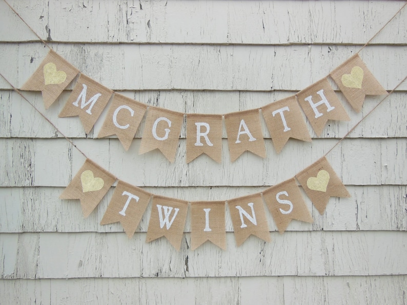 May include: A burlap banner with the text "McGrath Twins" in white letters. The banner is decorated with small yellow hearts.