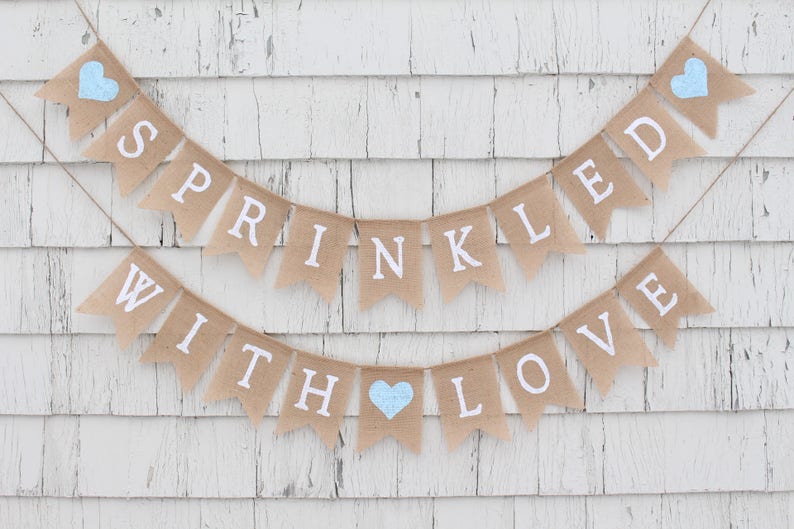 May include: A burlap banner with the text "Sprinkled with Love" in white letters. The banner is decorated with blue hearts.