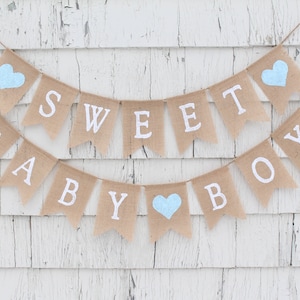 May include: A burlap banner with the words "Sweet Baby Boy" in white letters. The banner is decorated with three light blue hearts.