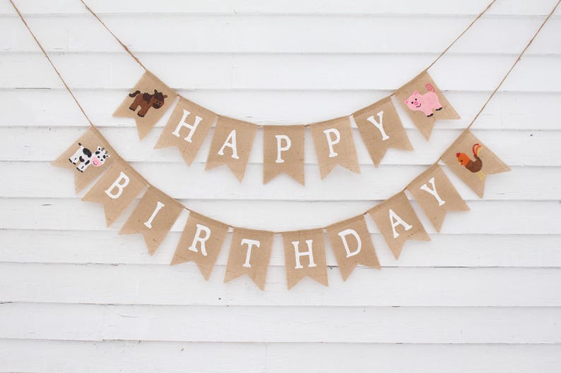 May include: A burlap banner with the words "Happy Birthday" in white letters. The banner is decorated with farm animal illustrations, including a cow, pig, horse, and rooster.