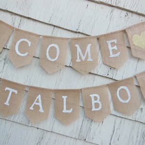Puede incluir: Una pancarta de arpillera con las palabras "Welcome Talbot" en letras blancas. La pancarta est&aacute; decorada con dos corazones dorados de purpurina.