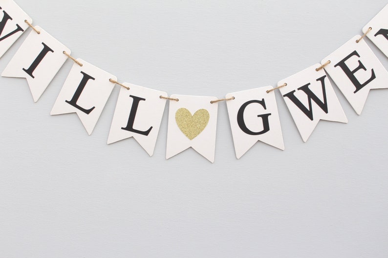 May include: White banner with black letters spelling "WILL LOVE" with a gold glitter heart in between the words.