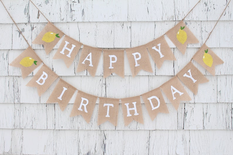 May include: A burlap banner with the words "Happy Birthday" in white letters. The banner is decorated with small yellow lemons.