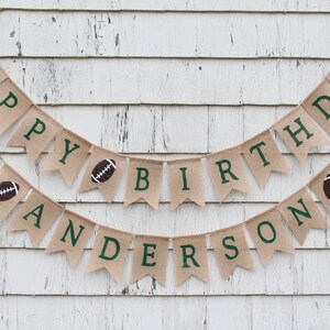 May include: A burlap banner with green letters spelling "Happy Birthday Anderson" with football graphics on each end.
