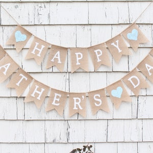 May include: A burlap banner with the words "Happy Father's Day" in white letters. The banner has three blue hearts.