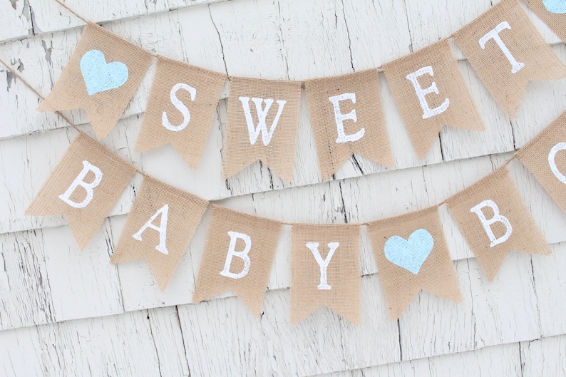 May include: A burlap banner with the words "Sweet Baby Boy" in white lettering. The banner is decorated with two light blue hearts.