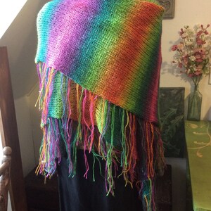 May include: A rainbow striped knitted shawl with fringe. The shawl is draped over a black mannequin.