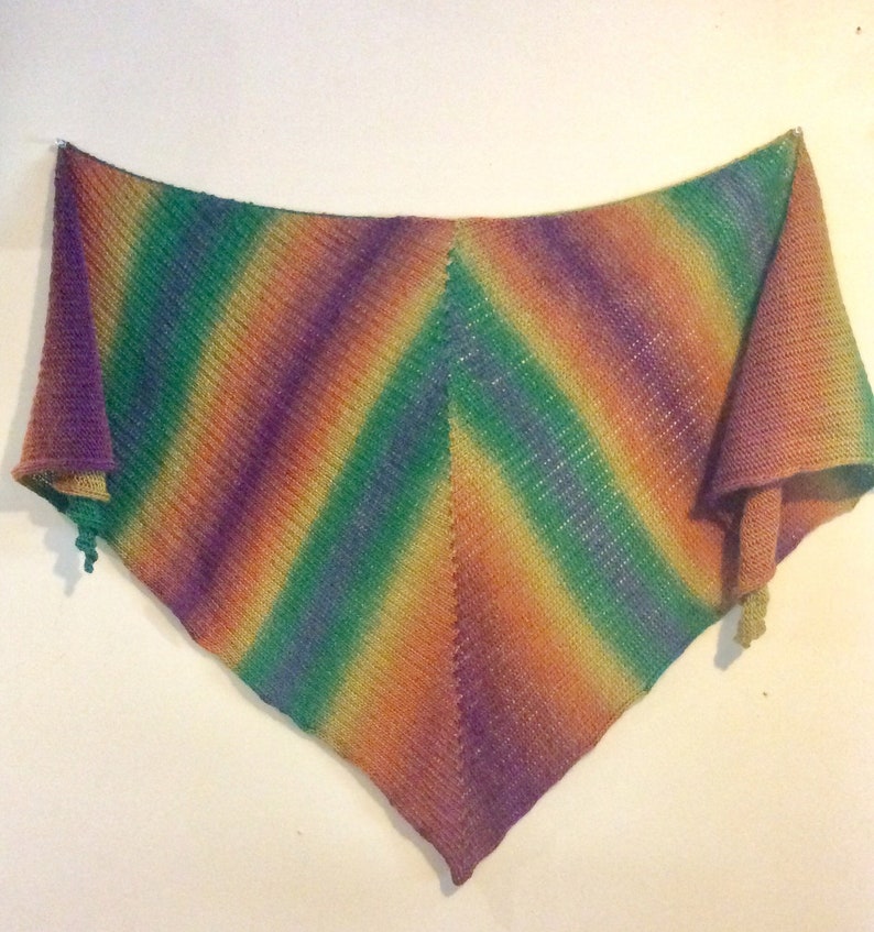 May include: A triangular crocheted shawl with a colorful ombre pattern in shades of purple, green, orange, and yellow.
