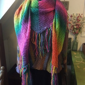 May include: A colorful knitted scarf with fringe, featuring a rainbow gradient of pink, orange, yellow, green, blue, and purple.