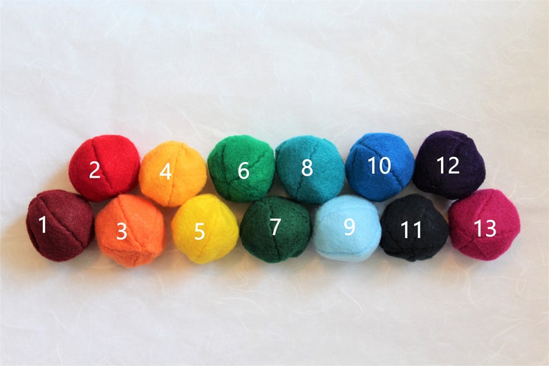 May include: Thirteen felt balls in a rainbow color pattern, numbered 1 through 13.