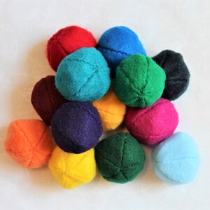 May include: A collection of 12 felt balls in various colors, including red, blue, green, purple, orange, yellow, and teal. The balls are arranged in a pile on a white surface.