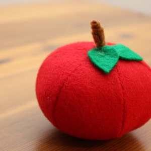 May include: A red felt apple with a brown stem and a green felt leaf.