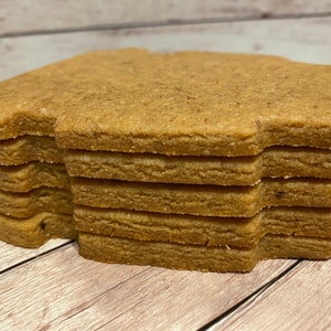 May include: A stack of eight brown gingerbread cookies in the shape of a house.