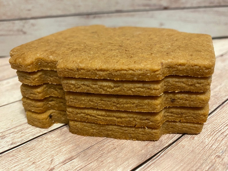 May include: A stack of eight brown gingerbread cookies in the shape of a house.