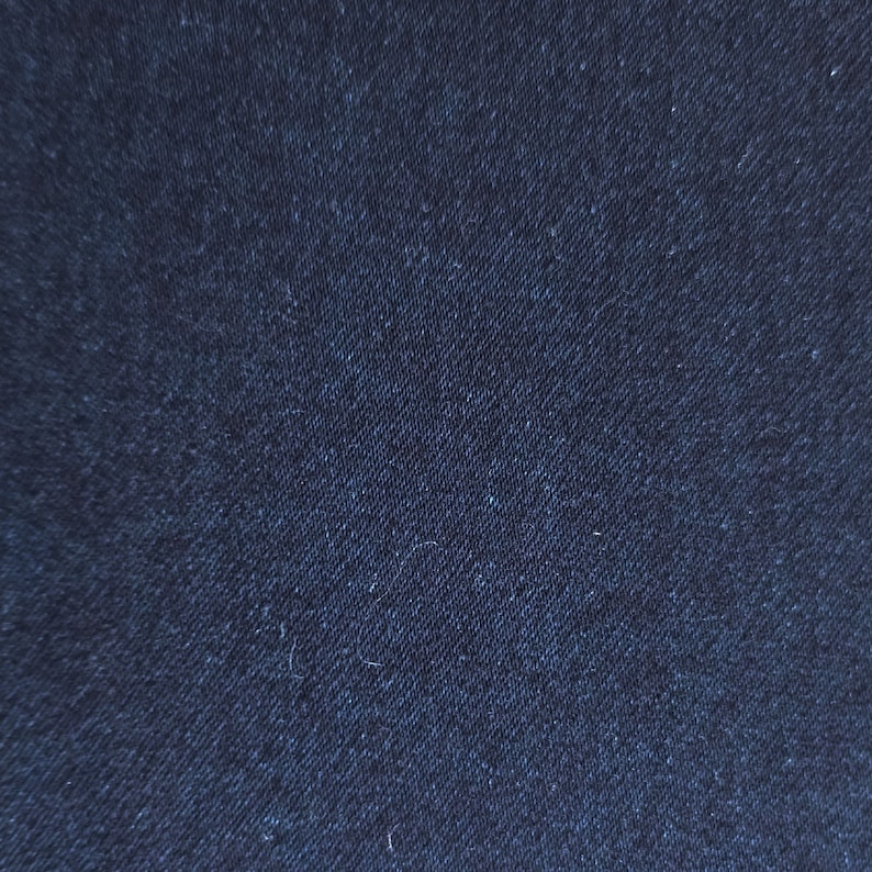 May include: Close-up of dark blue denim fabric with a woven texture.