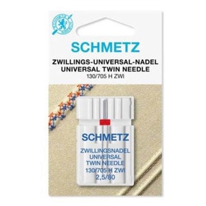 May include: A Schmetz Universal Twin Needle pack. The white package features blue and red text, with the Schmetz logo at the top. The needles are for sewing machines, labelled 130/705 H ZWI. The package also states "Zwillingsnadel Universal Twin Needle 2,5/80".