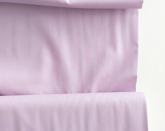 Könnte beinhalten: Nahaufnahme eines helllila Stoffes, der in der Hälfte gefaltet ist. Der Stoff hat eine glatte, weiche Textur.