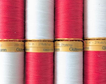 Op de afbeelding: Close-up van spoelen garen in afwisselend rood en wit. De spoelen zijn voorzien van het merk "Gütermann" en metingen van 250 meter of 274 yards.