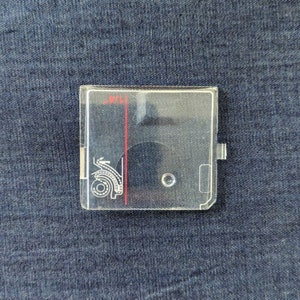 May include: A clear plastic sewing machine foot with a red line and the word "WILL" written on it. The foot has a small hole in the centre and a design on the left side.