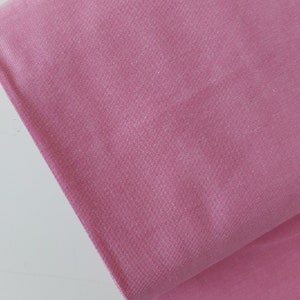 May include: A close-up of a soft, pink fabric with a slightly textured surface.