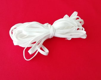 Könnte beinhalten: Ein weißes Gummiband, gefaltet und aufgerollt, vor einem roten Hintergrund.