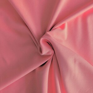 Peut inclure: Un gros plan sur un tissu doux et rose à la texture lisse. Le tissu est plié et drapé, mettant en valeur son drapé et son écoulement.