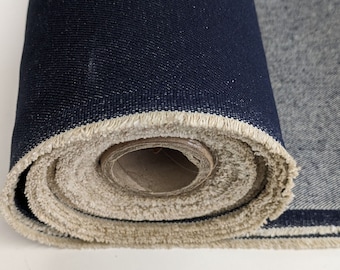May include: A roll of dark blue denim fabric with a beige edge. The fabric is rolled up and the end of the roll is visible.